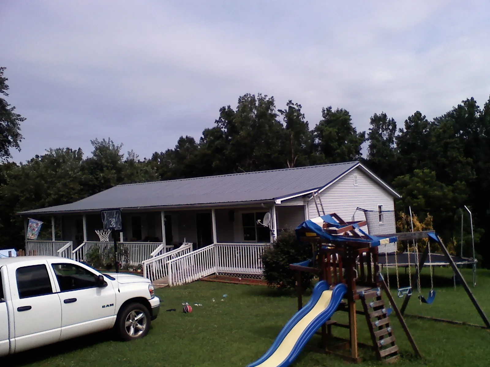 Dark metal roof on a country home with a full length front porch in Keene