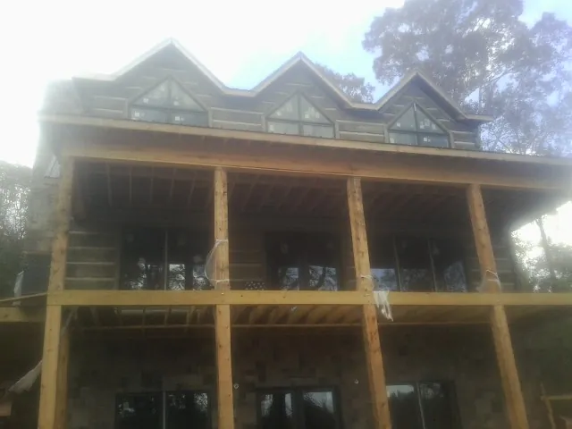 Dormers and porch framing on a large log home under construction — Roof Coating work by our crew in Keene